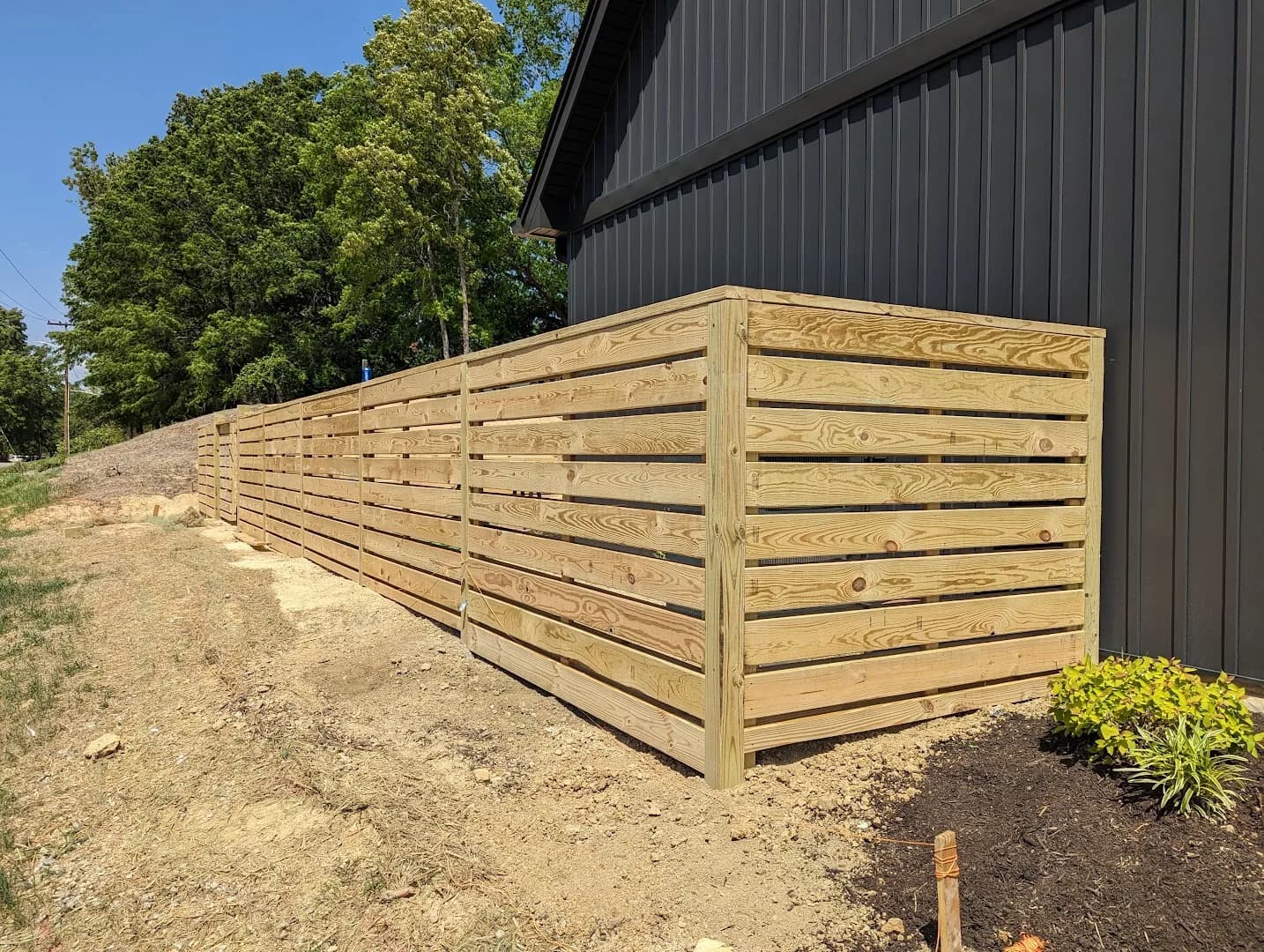 Completed horizontal wood privacy fence beside a building
