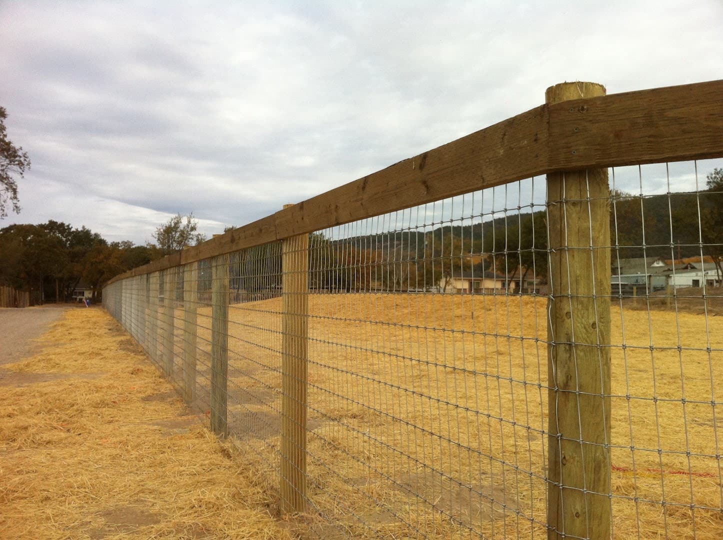 Wood post and woven-wire field fence surrounding an open property