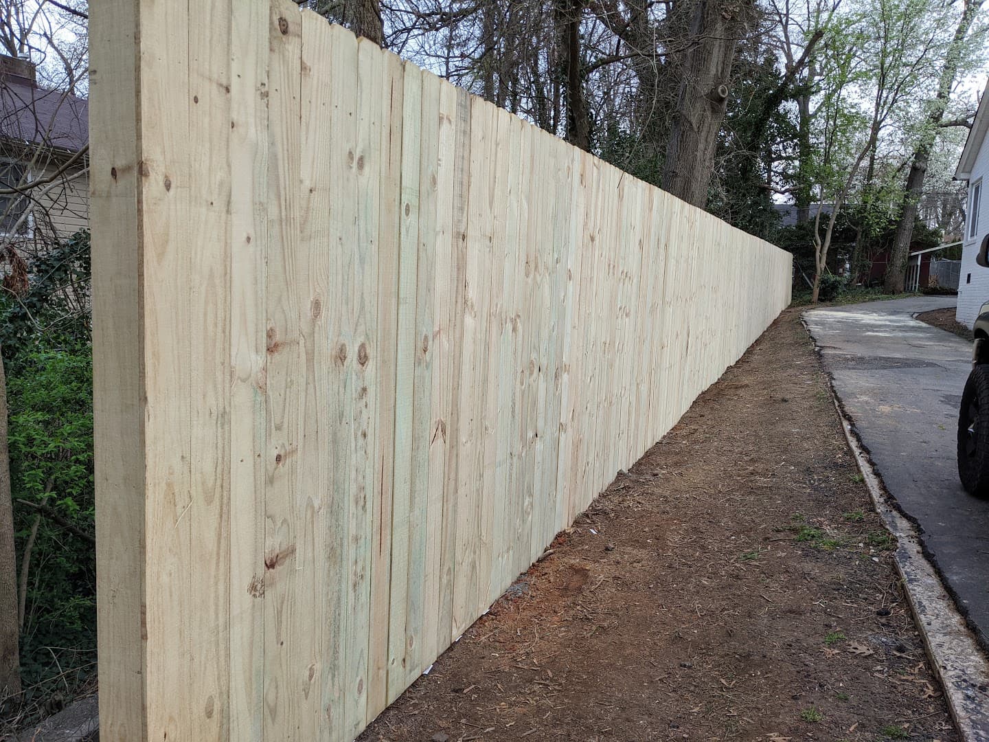 Long new wood privacy fence installed beside a driveway in High Point, North Carolina