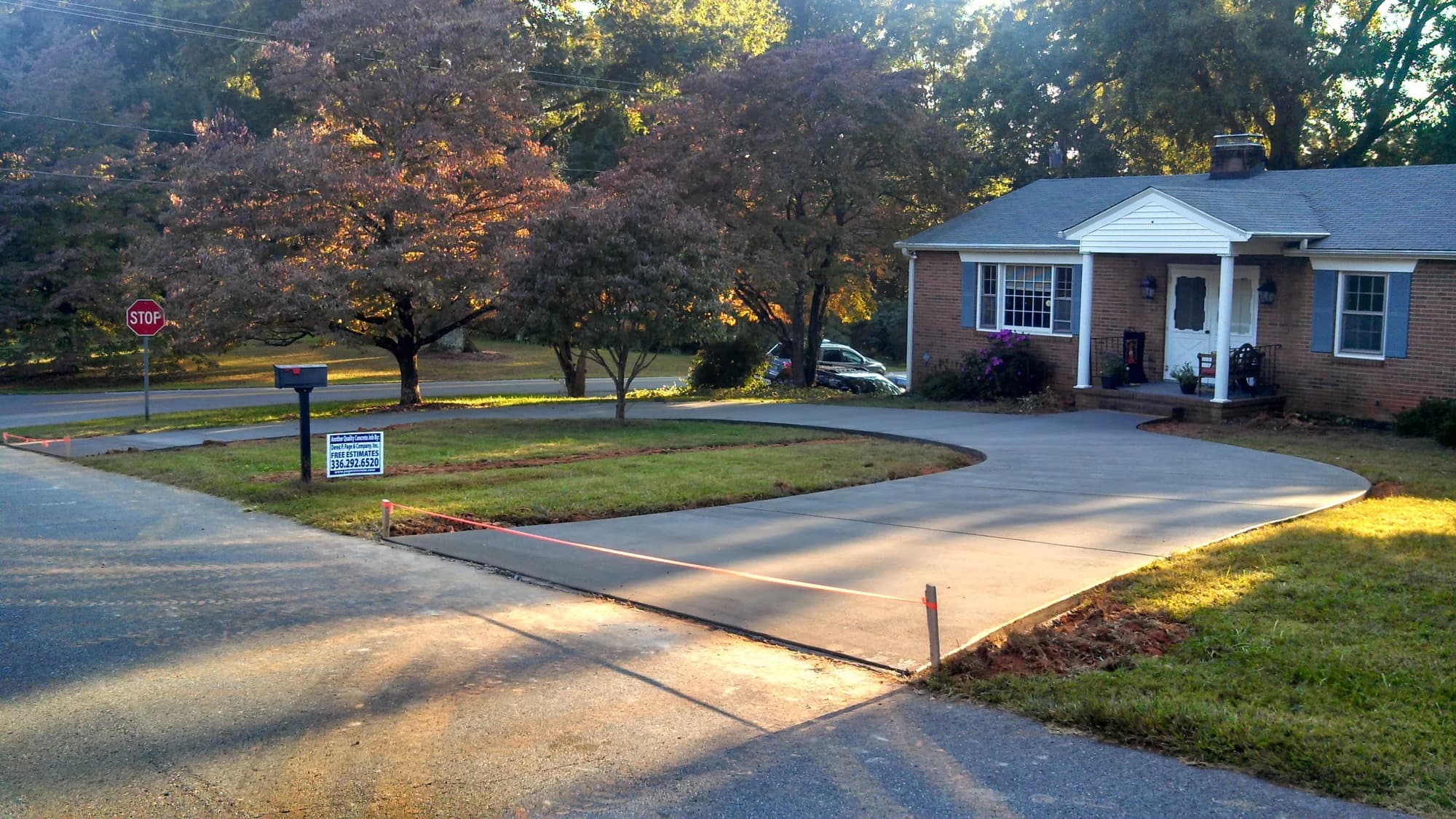Curved concrete driveway leading to a carport at a brick home