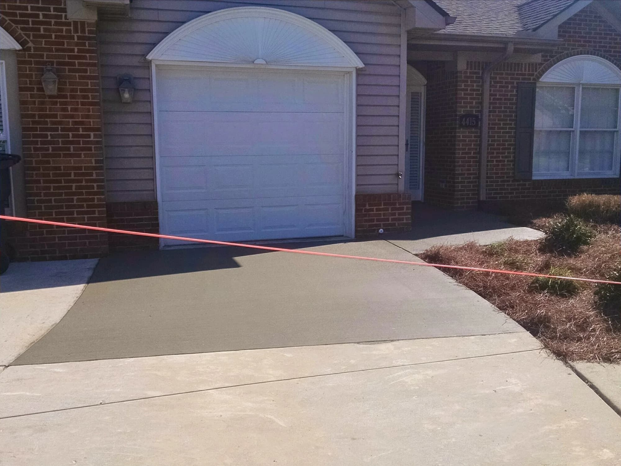 Fresh concrete driveway section in front of a single-car garage