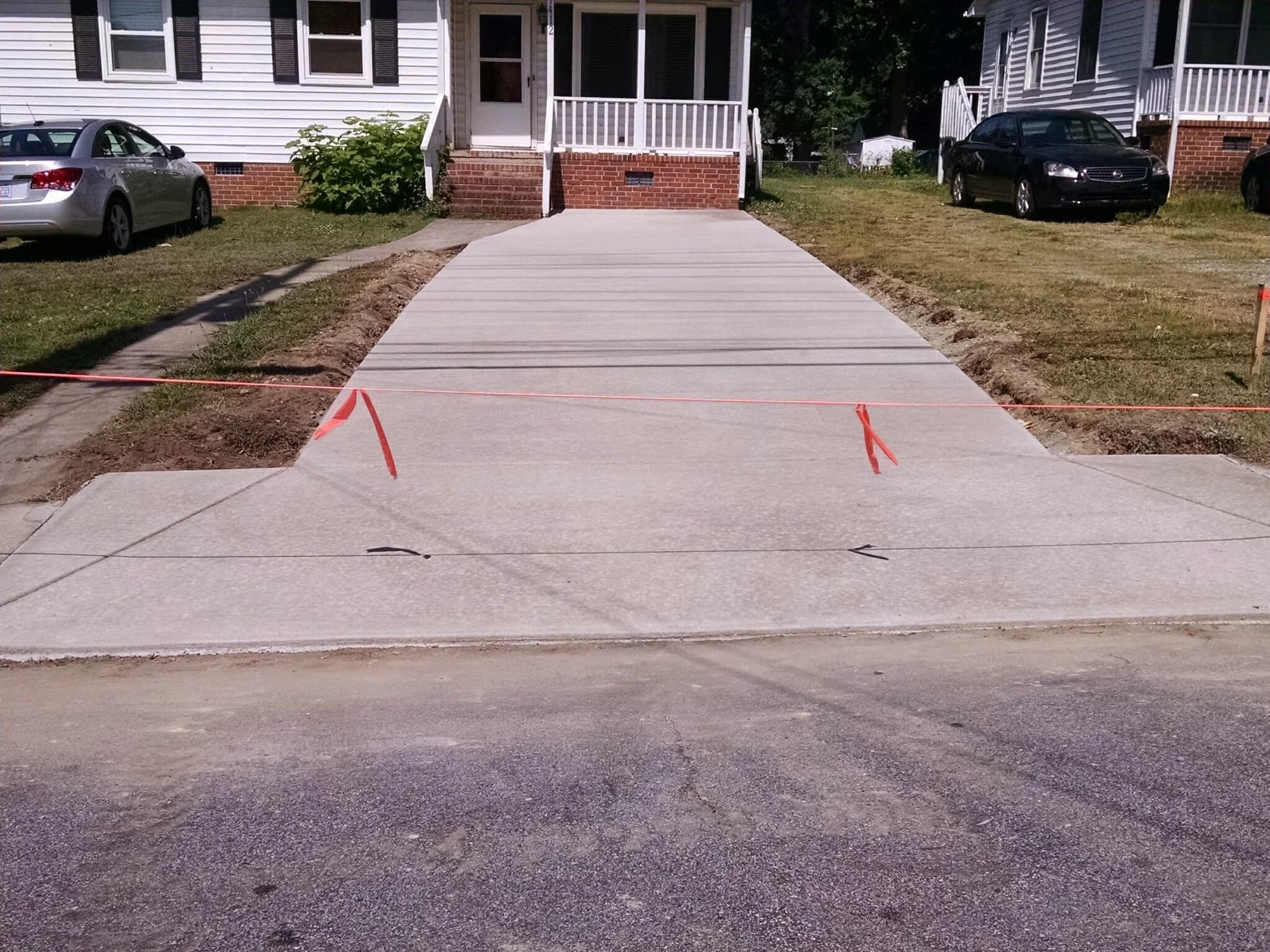 Concrete driveway with a flared street entrance beside a front lawn