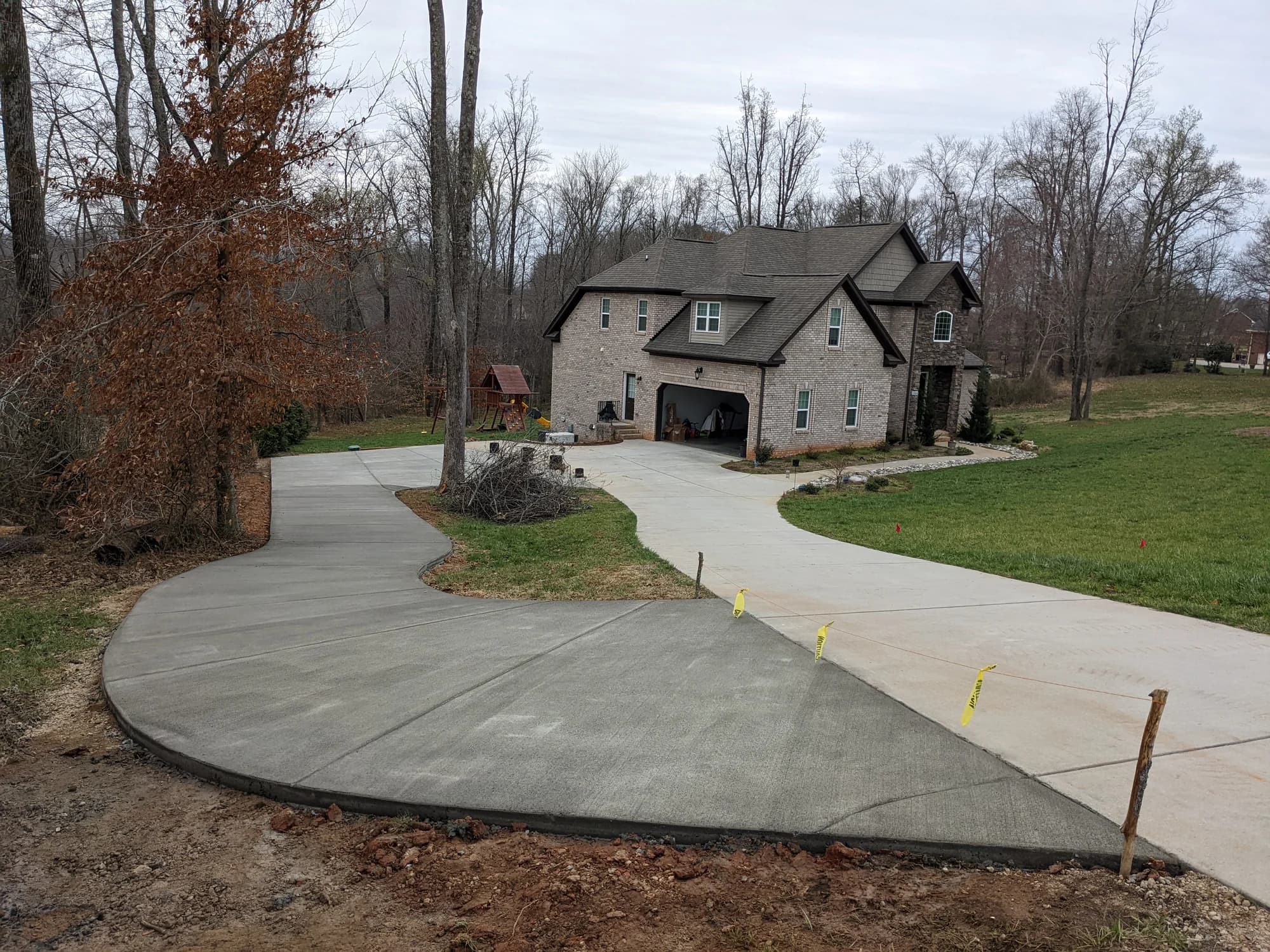 Curved concrete driveway wrapping around a landscaped island at a stone home