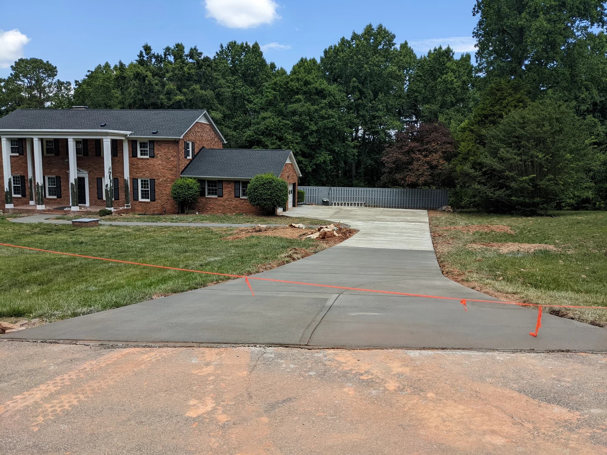 Concrete driveway with a curved edge and wide street apron at a brick home