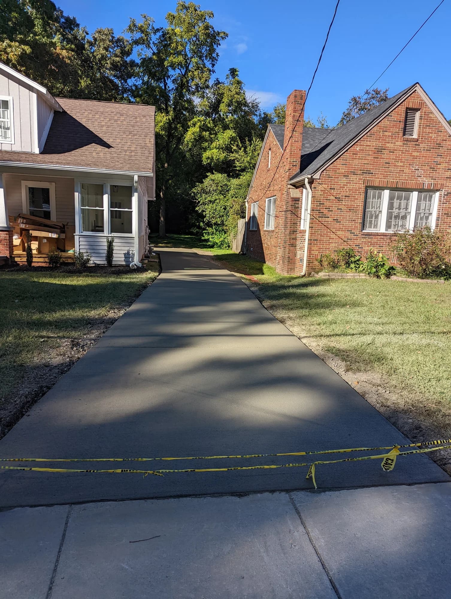 Fresh concrete driveway running between two brick homes