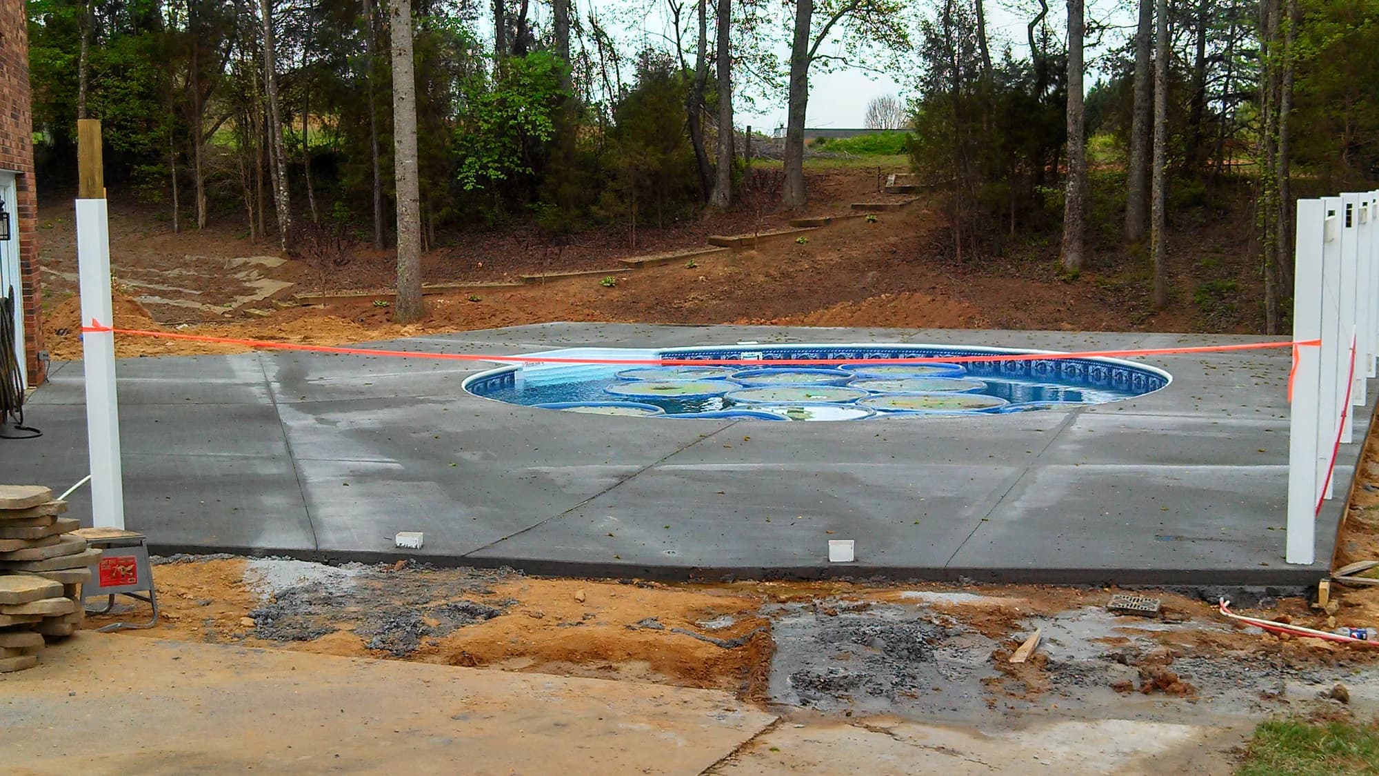 Fresh concrete patio surrounding a small backyard swimming pool