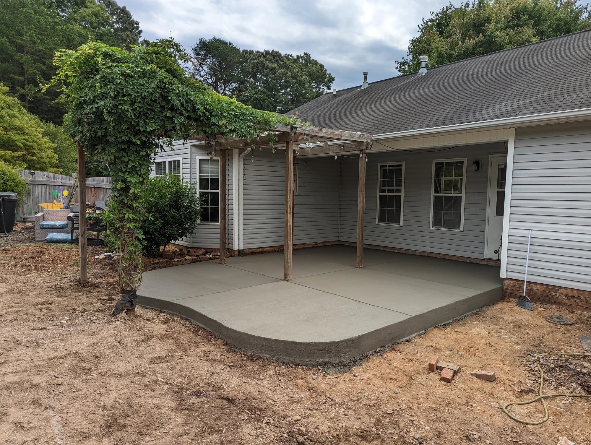 Concrete patio with a rounded corner beneath a covered back porch