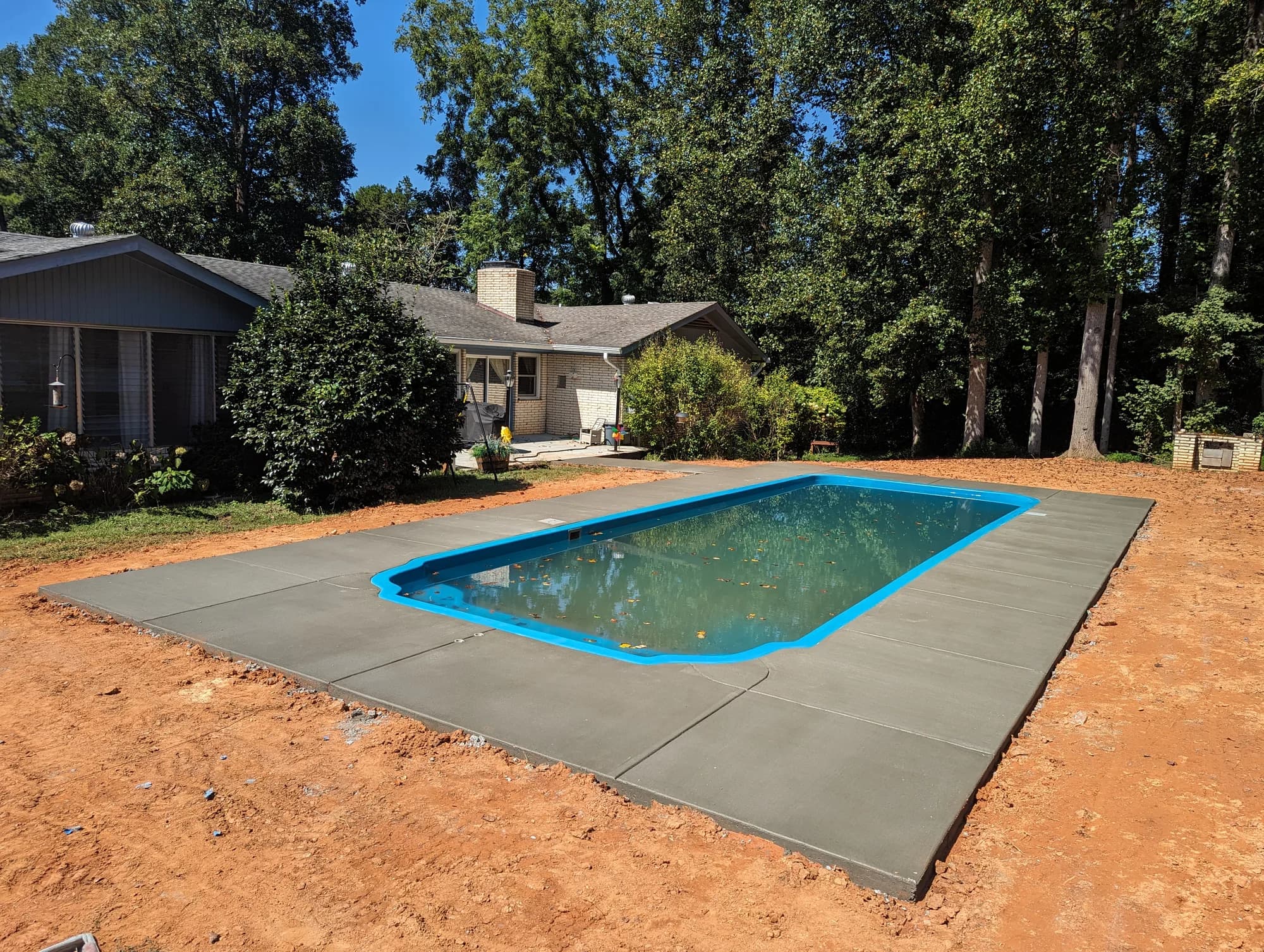 Fresh concrete deck surrounding a rectangular backyard swimming pool