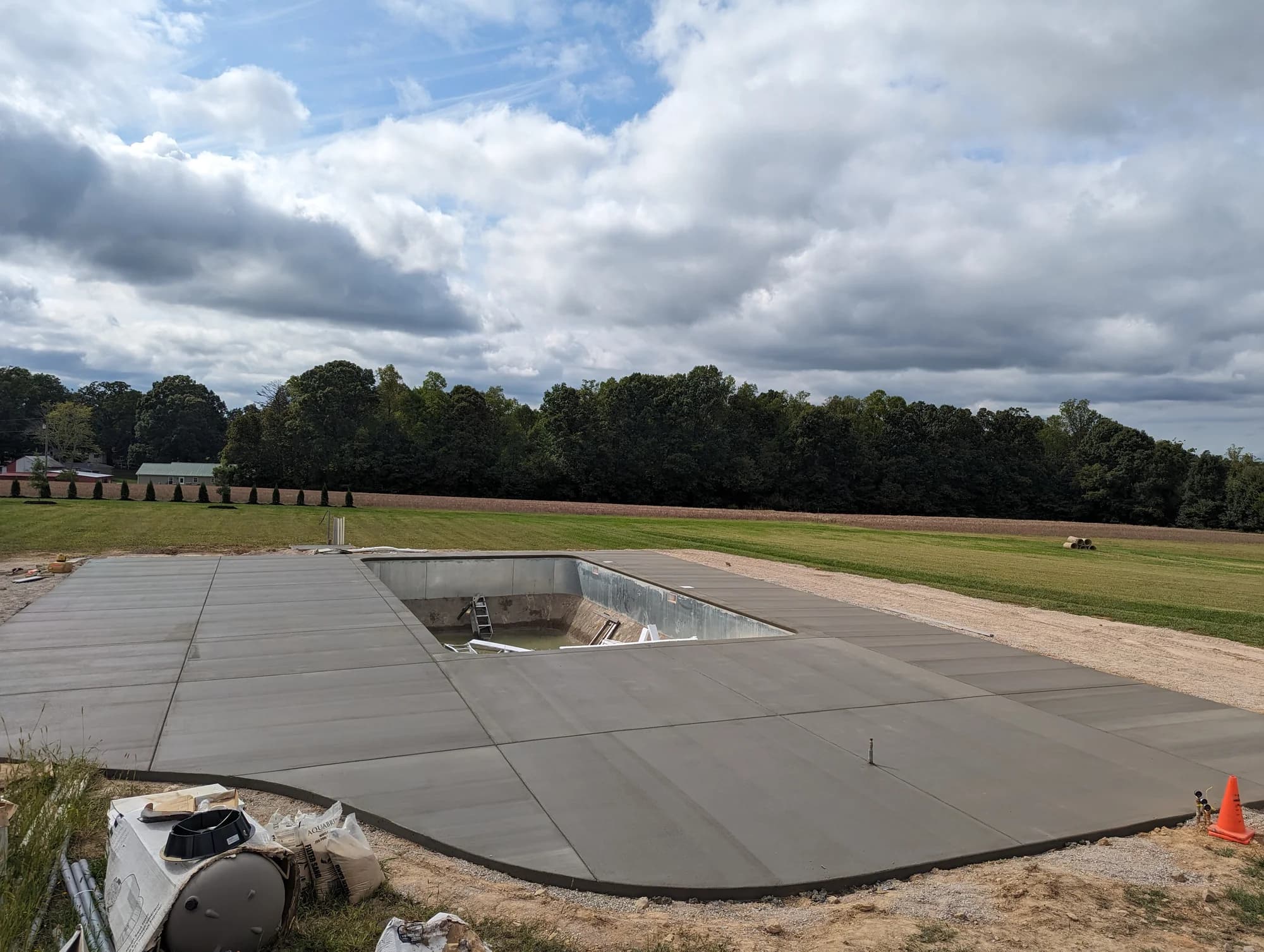 Wide concrete pool deck with a view across open fields