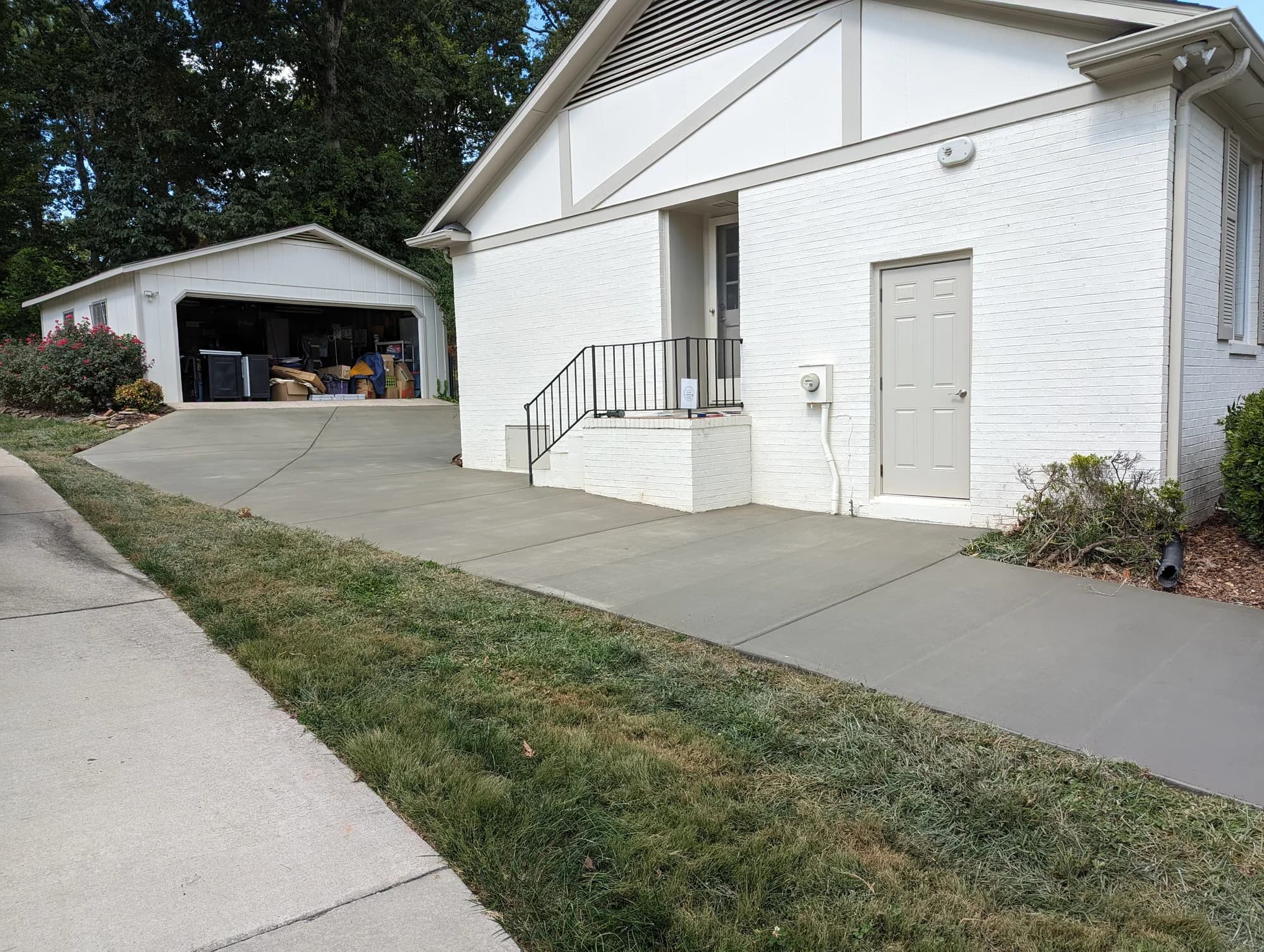Concrete patio and walkway beside a white brick home and back steps