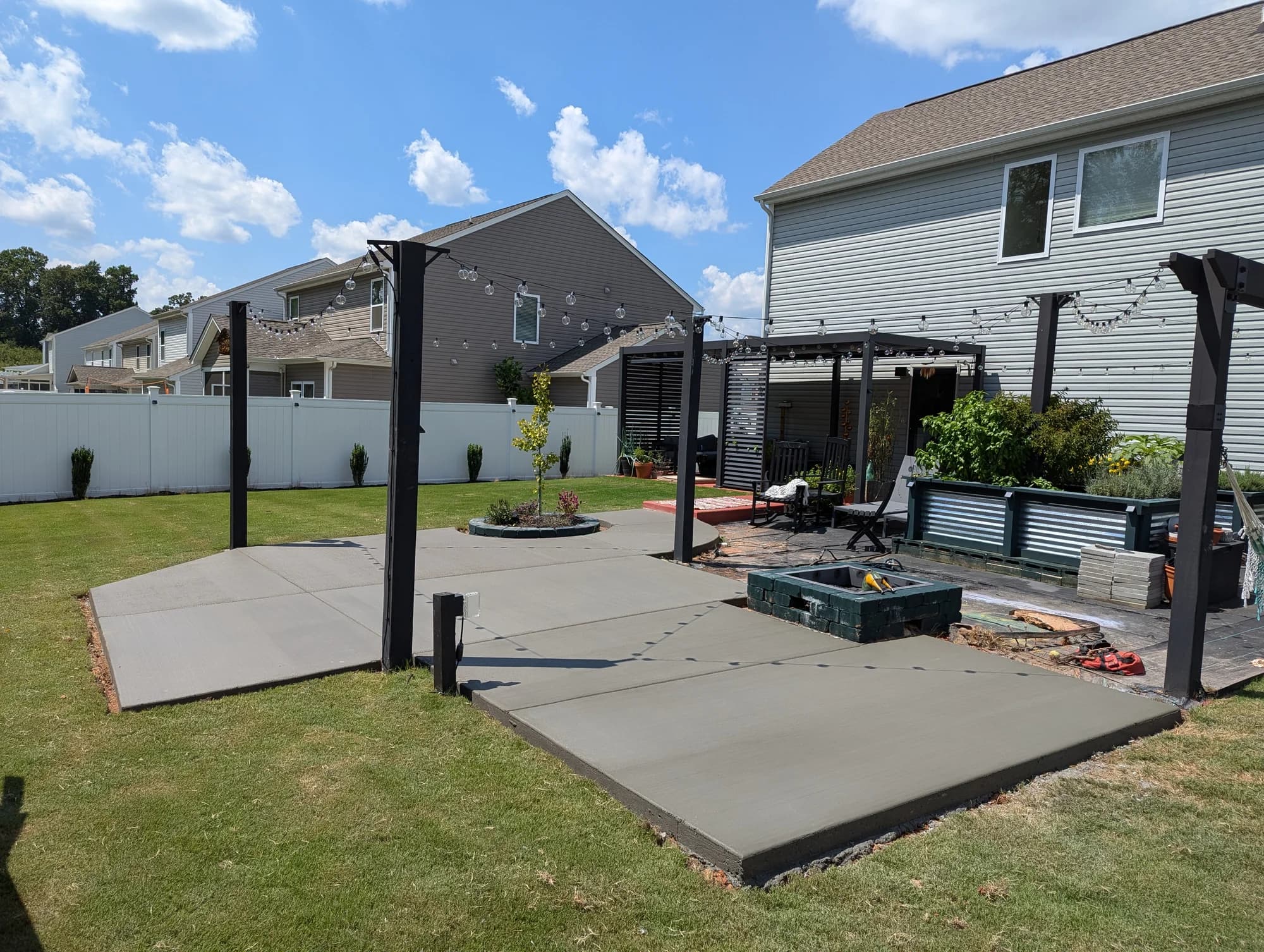 Concrete backyard patio with pergola posts and an outdoor seating area
