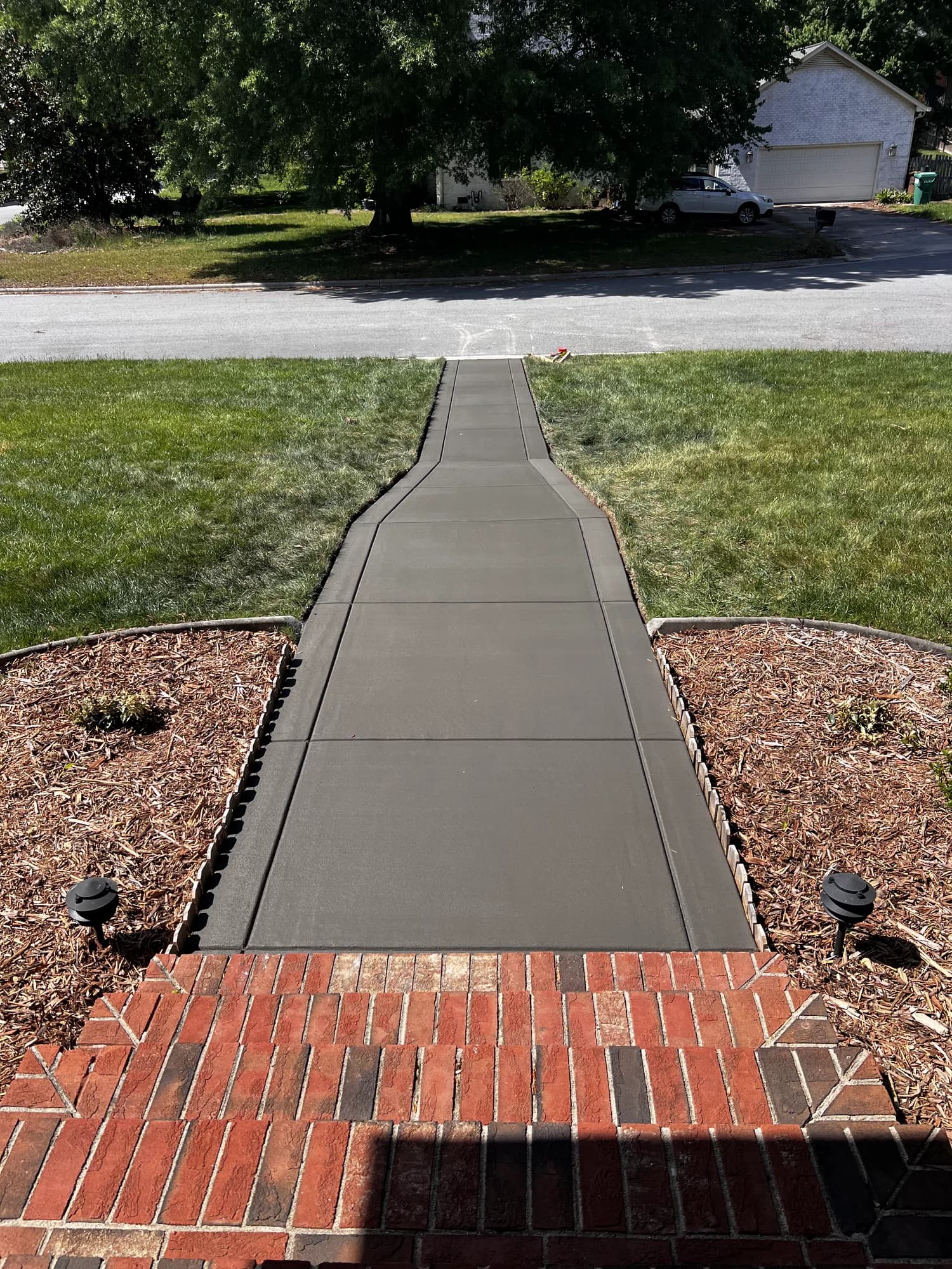 Concrete walkway with contrasting borders extending from brick entry steps to the street