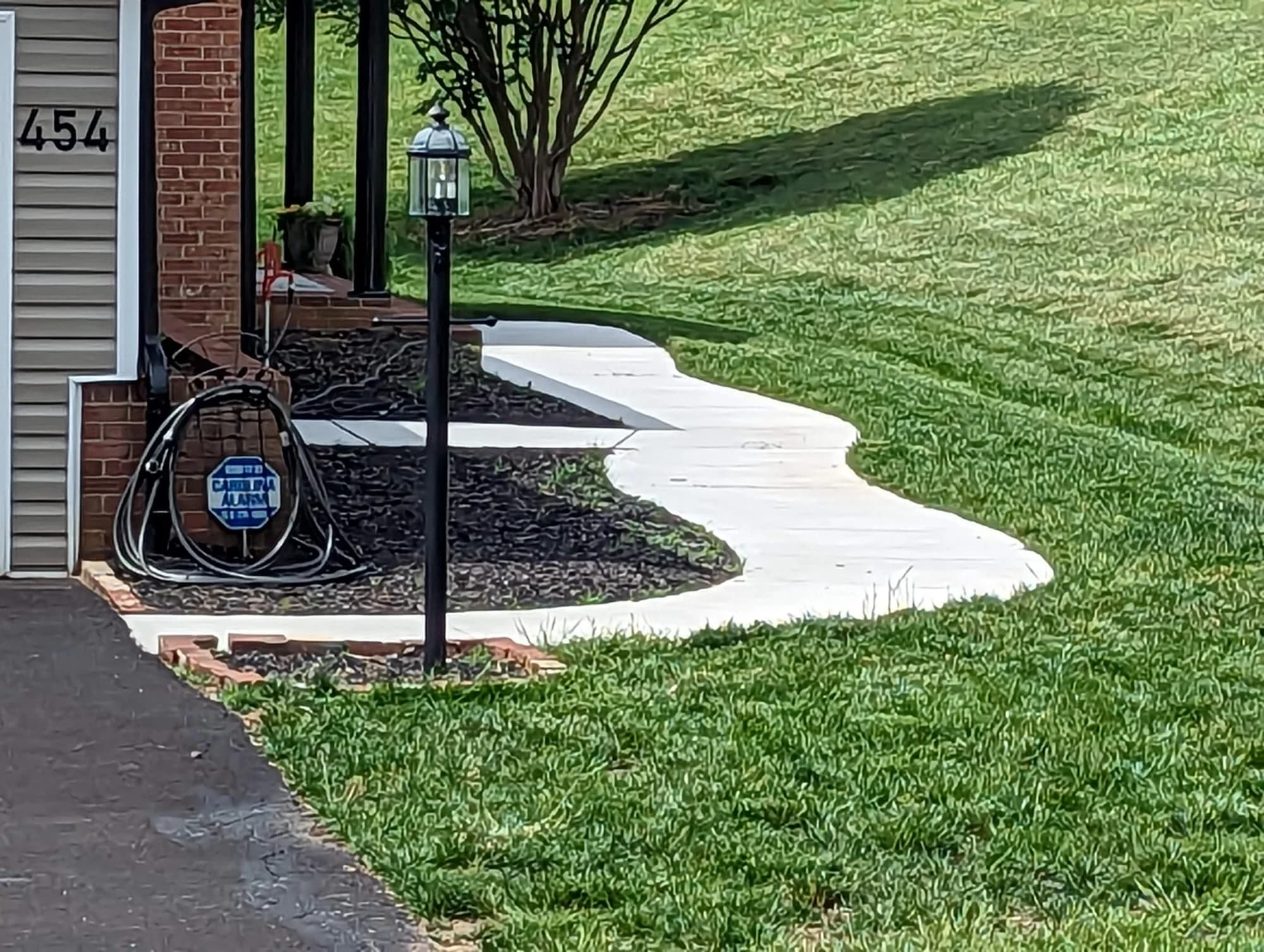 Curved concrete entry walkway beside a landscaped front lawn