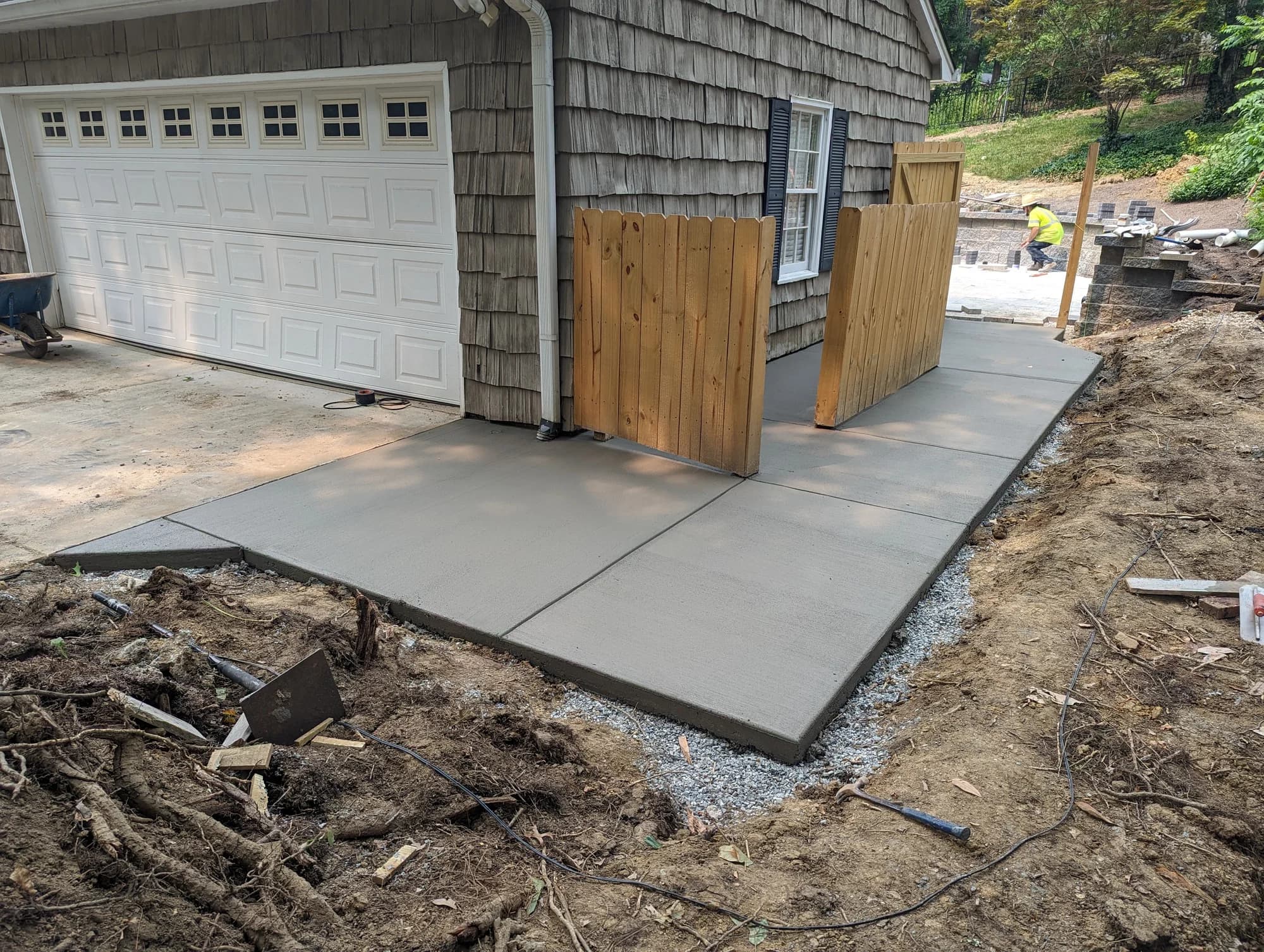 Concrete walkway wrapping around a detached garage and wooden gate