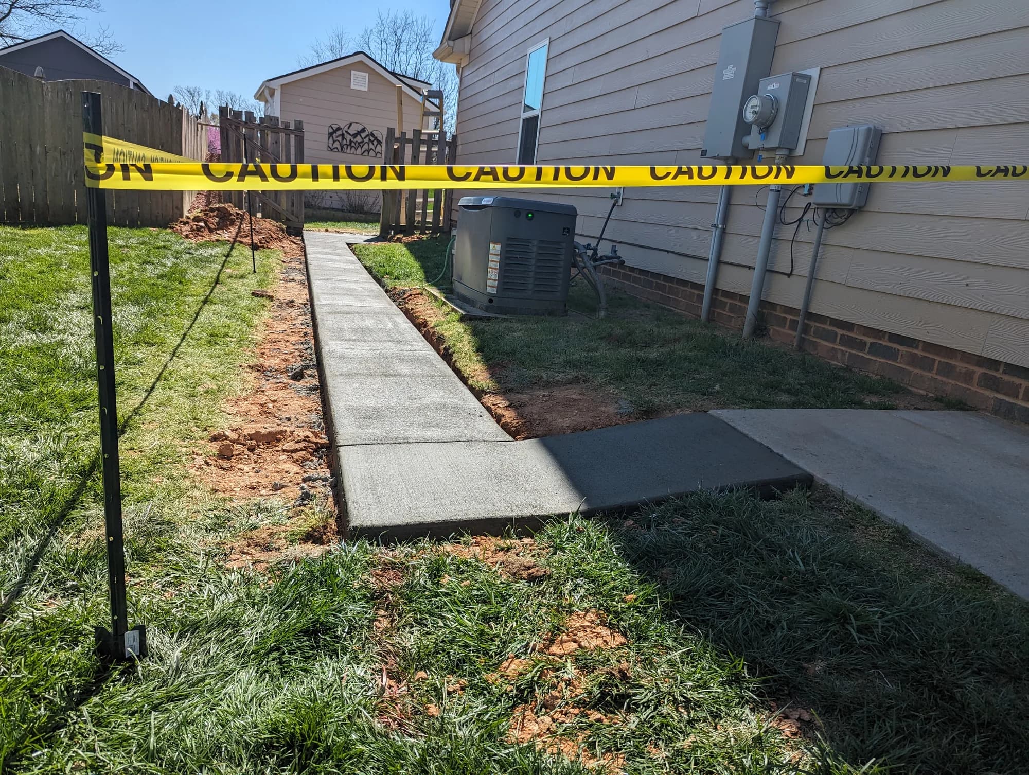 Fresh concrete walkway running beside a home with a connecting path