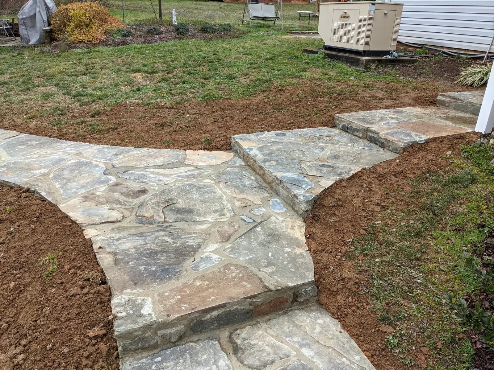 Stone-finish walkway and steps descending through a lawn to a back door
