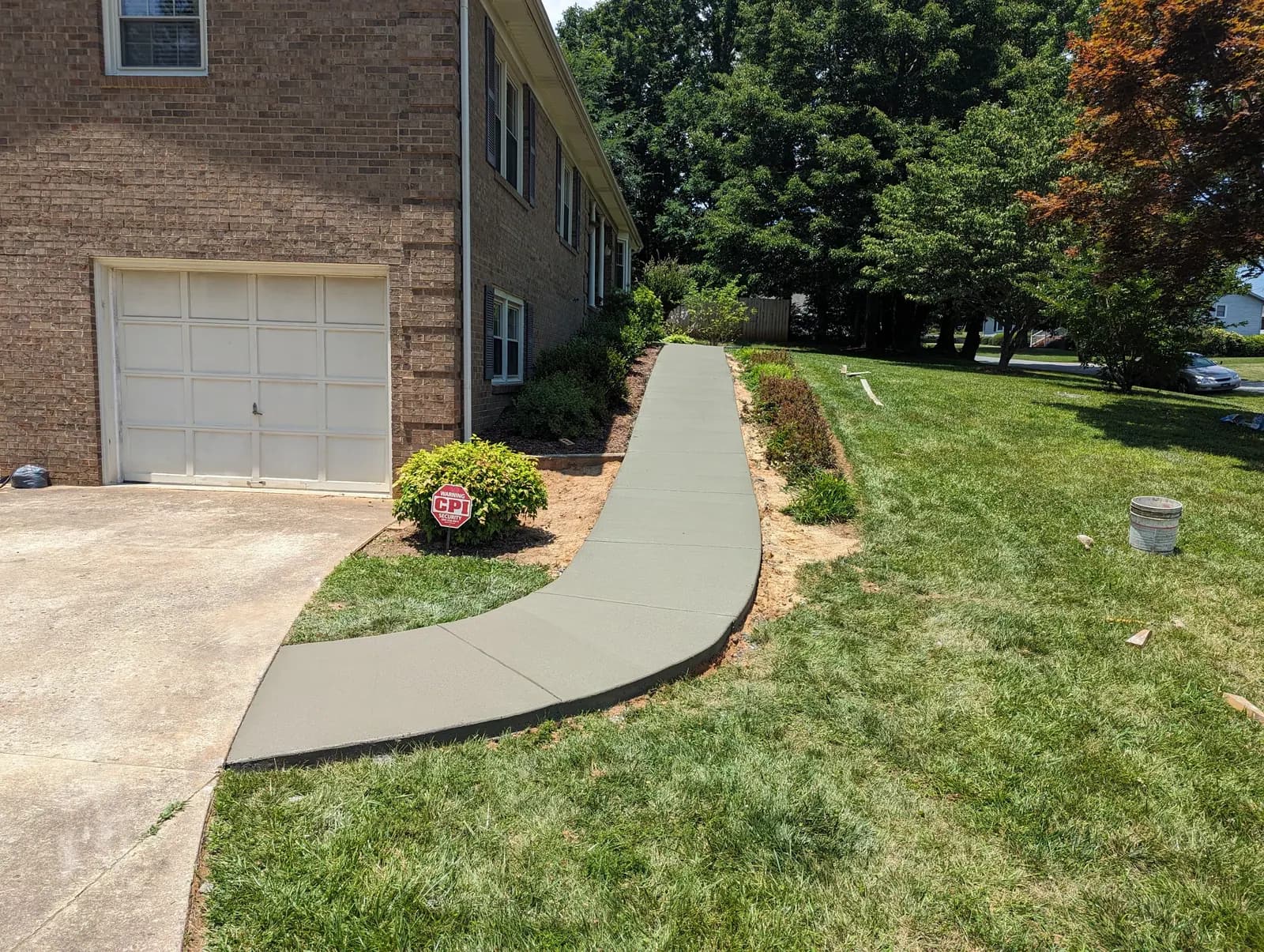 Finished curved concrete walkway following the side of a brick home