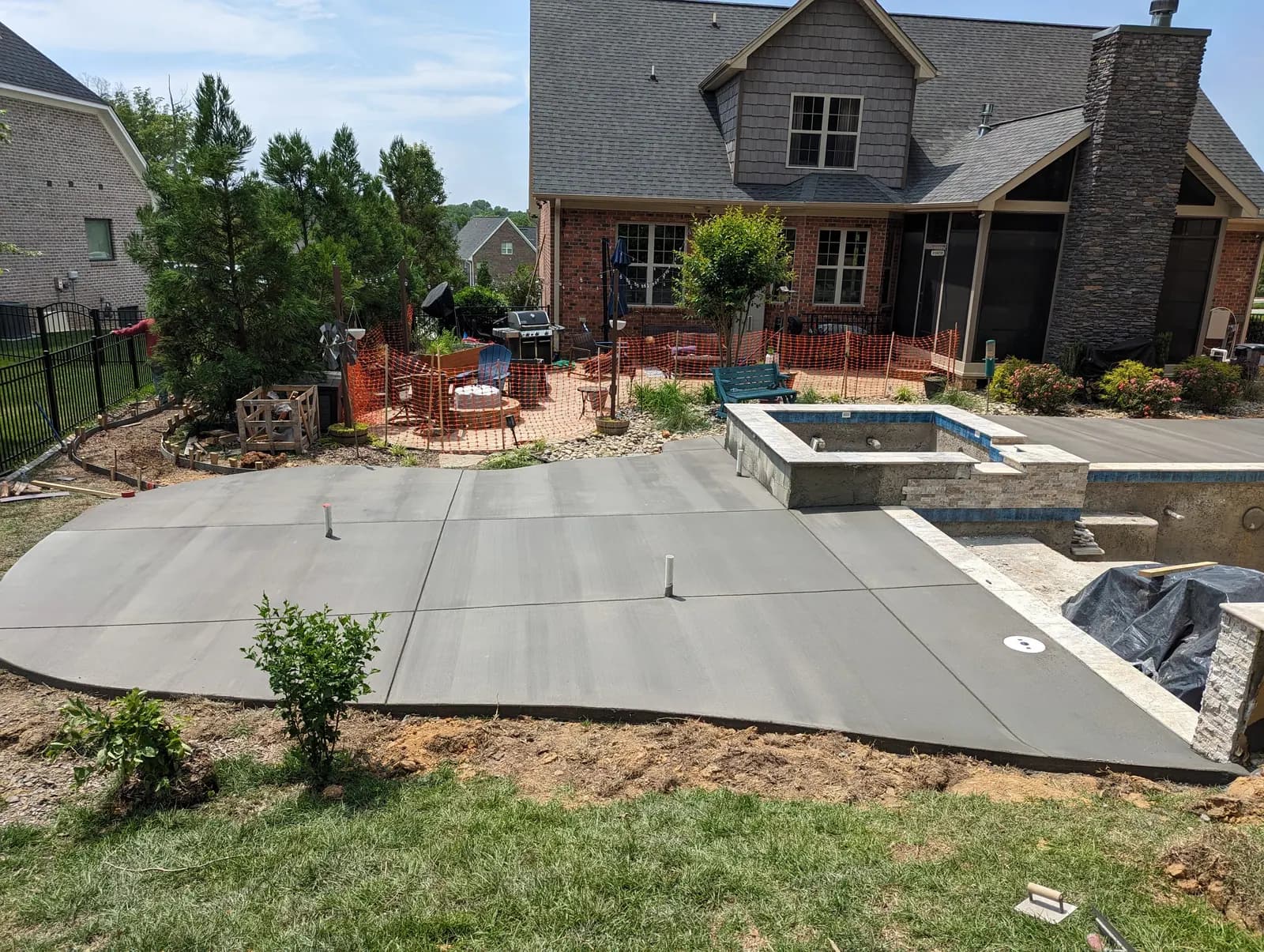 Fresh concrete pool deck poured around a stone spa surround