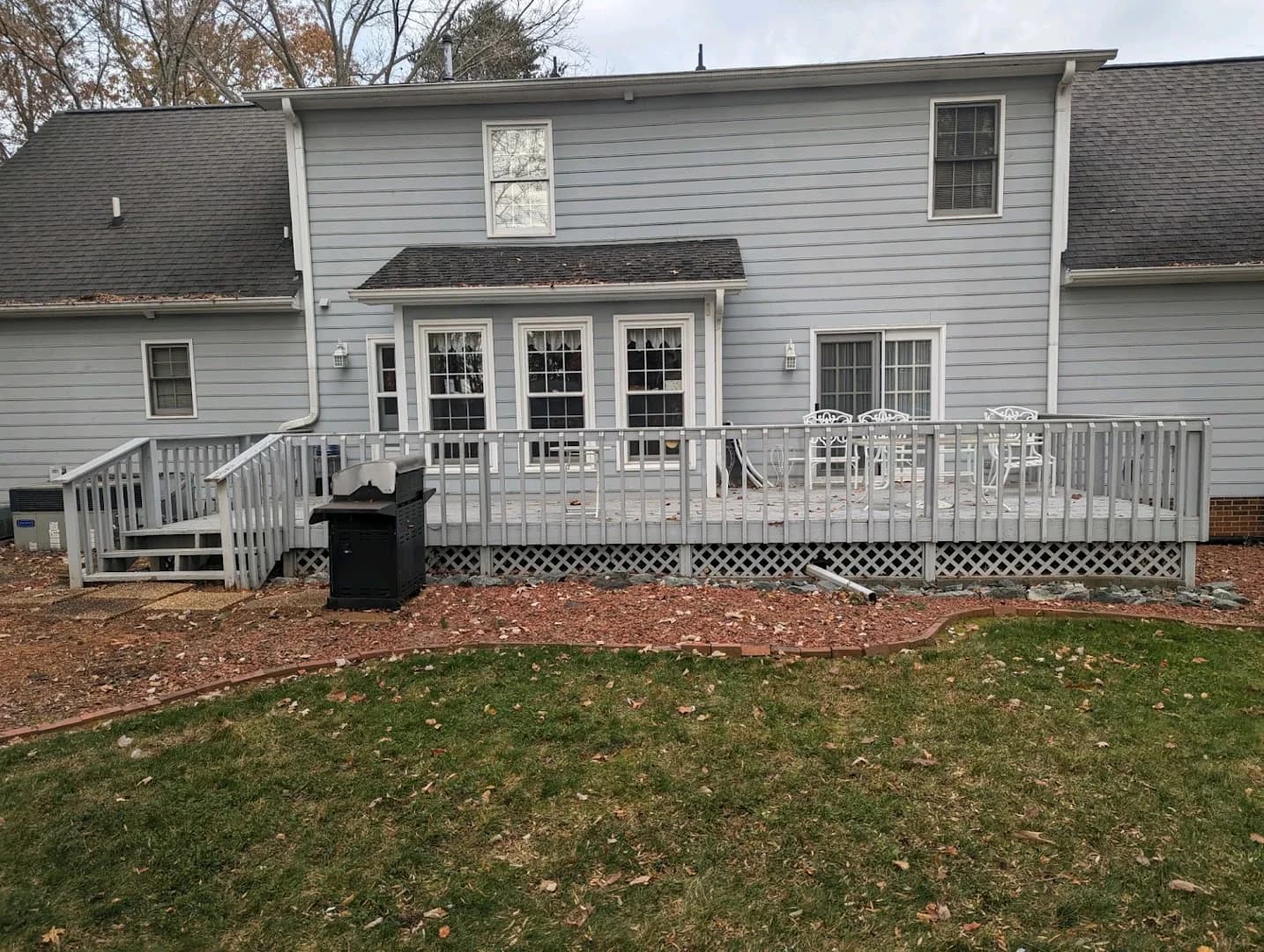 Completed gray composite backyard deck with white posts and black balusters