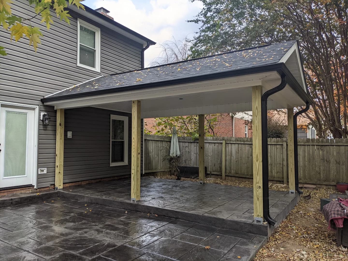 Roofed wood porch with steps and black metal balusters