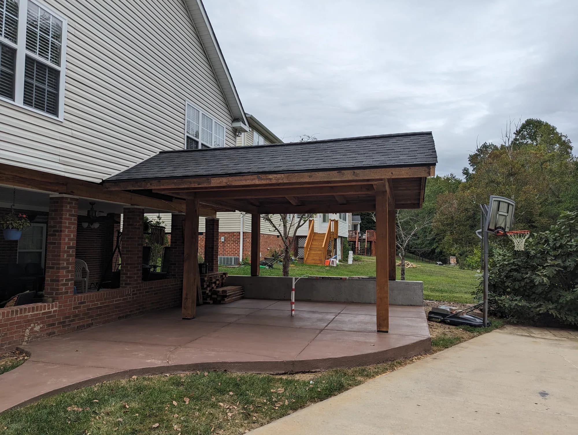 Timber pavilion connected to a home and set over a finished concrete patio