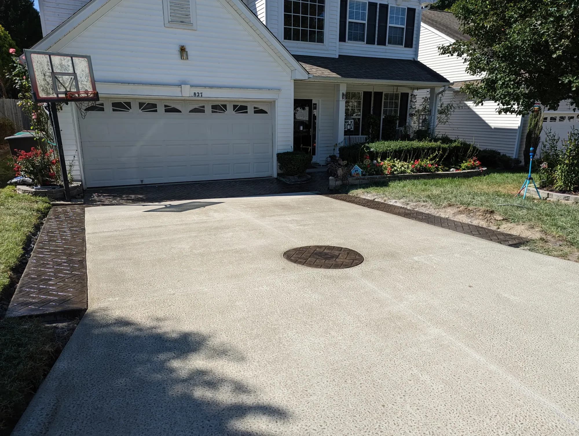Concrete driveway with a broom finish, herringbone stamped border and brick circle in High Point, NC