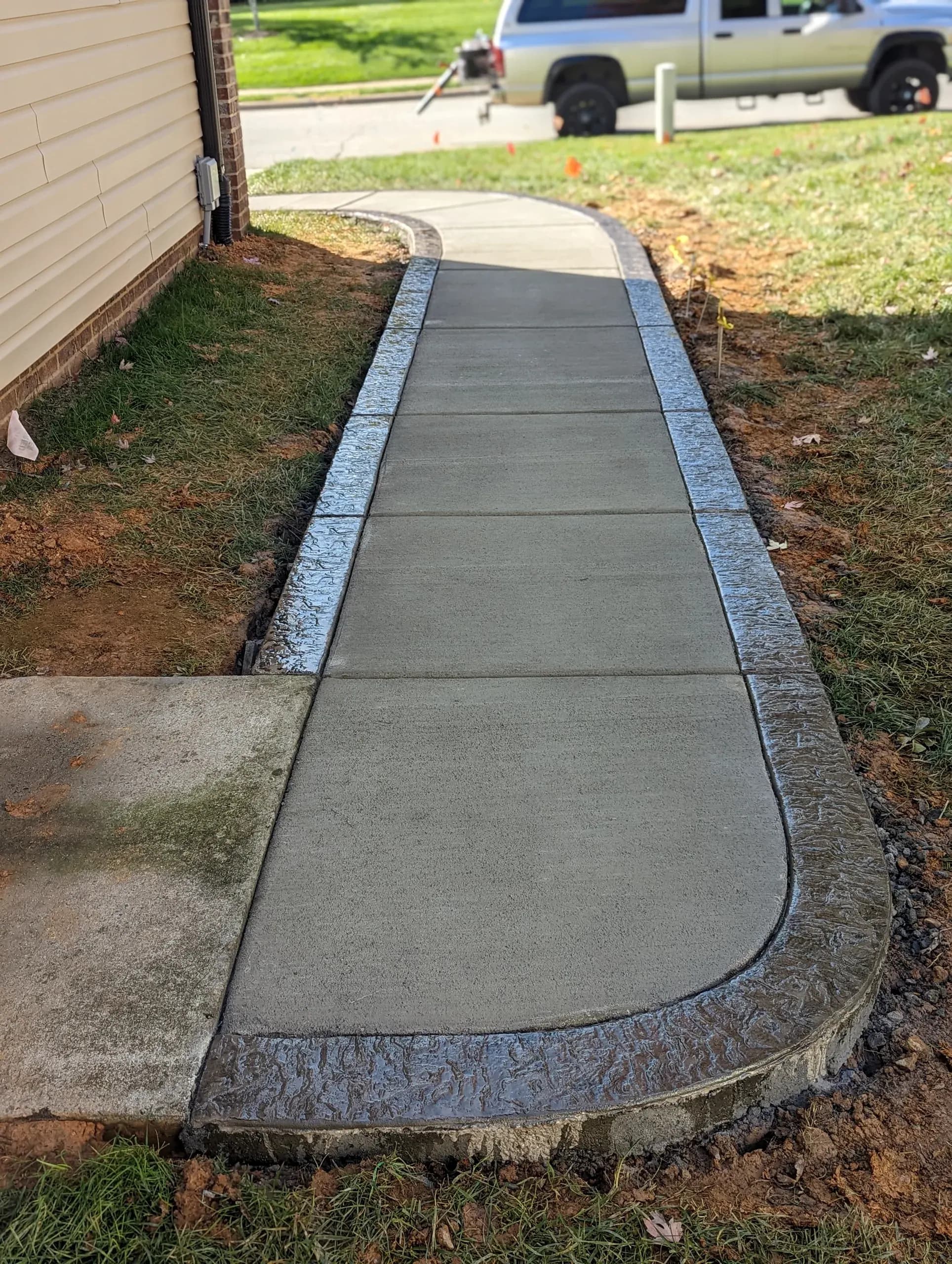 Concrete walkway with a broom finish and stamped border in Greensboro, NC
